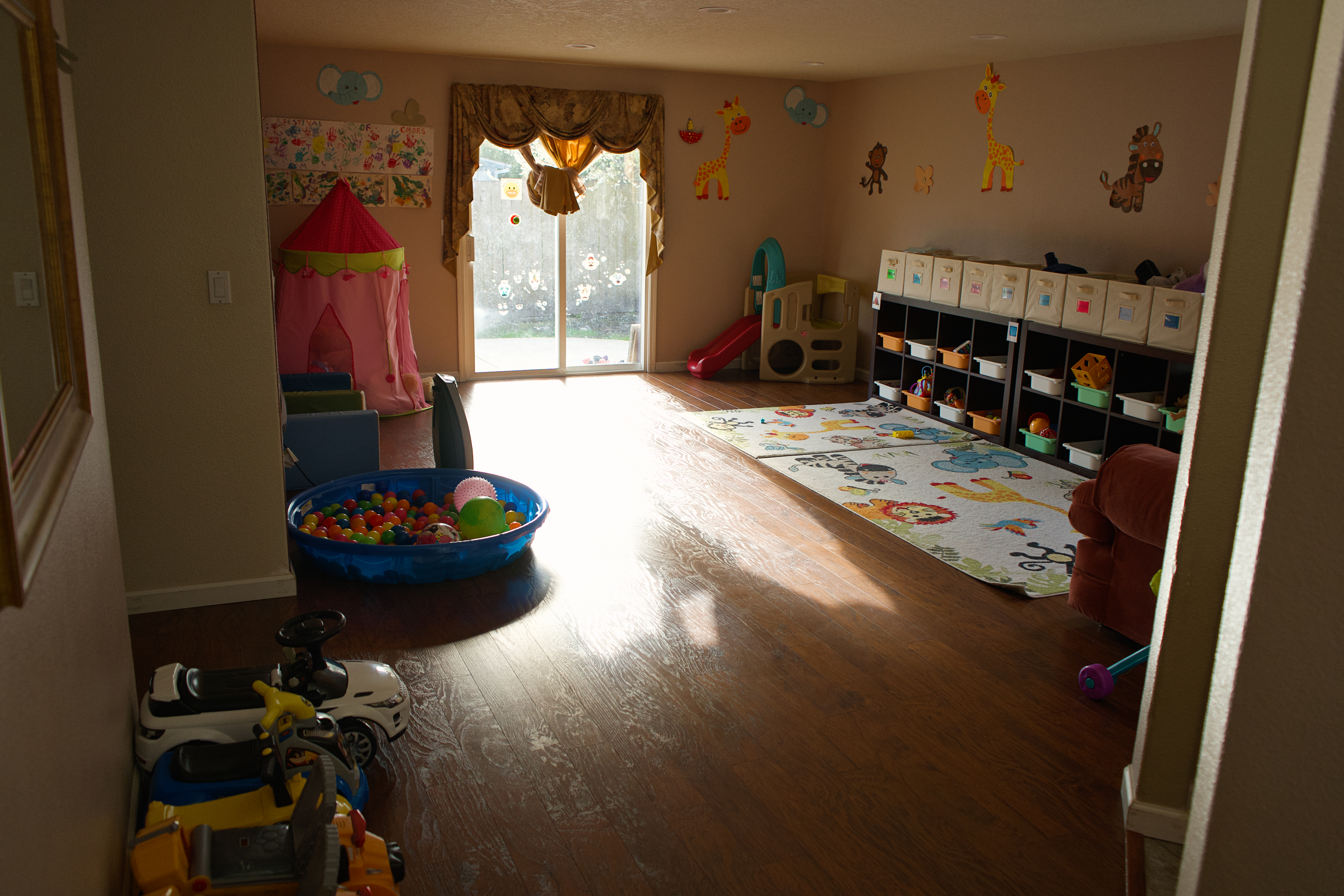Cozy reading corner with soft seating, toys, plushies, and baskets of books.